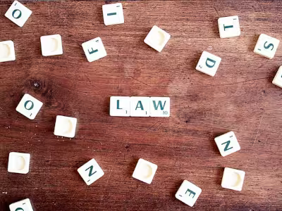 Una mesa de madera con las fichas de scrabble en la que pone LAW