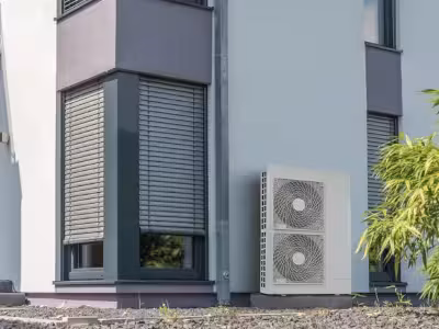 Ilustración de una casa equipada con sistema de aerotermia, energía eficiente para climatización y agua caliente sanitaria